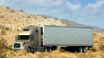 Long-haul truck driving through desert for road freight and transport services